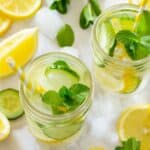 Fruit infused pretty water on a table with fresh lemons and cucumbers that are great for your skin.