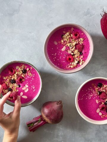 "Heart Beet Love" smoothie made with beets and strawberries in a bowl on a table decorated with beets.