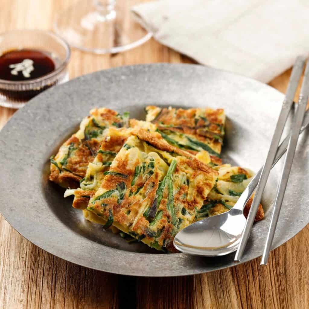 Korean pancakes in a grey dish served with gluten free soy sauce on the side.