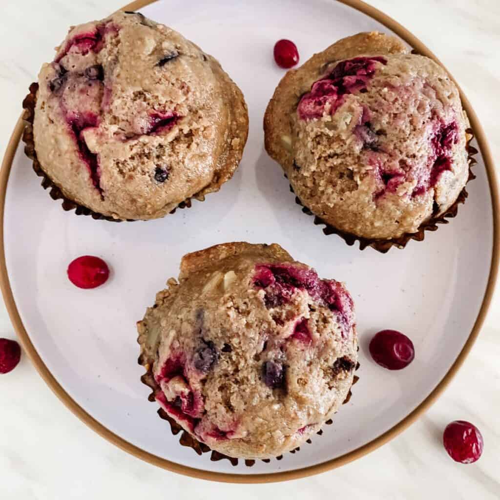 Vegan superfood mixed berry muffins on a ceramic plate with cranberries.