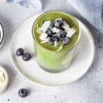 Delicious hormone-balancing green smoothie topped with fresh blueberries and coconut flakes, gluten free recipe for good gut health and healing.